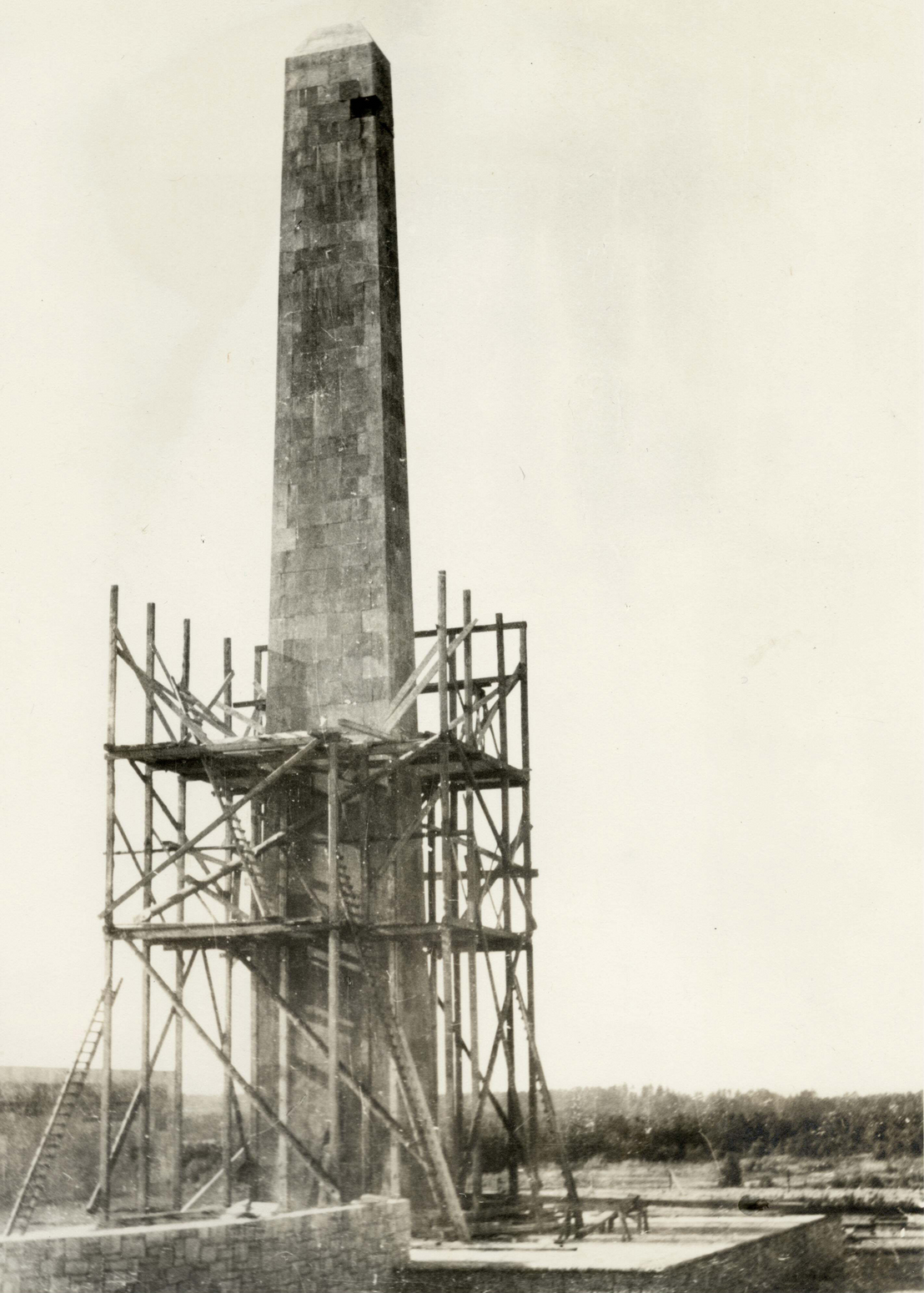Obelisk mit Gerüst auf dem Gelände der Gedenkstätte Bergen-Belsen, vermutlich Renovierungsarbeiten, ca. 1960. Niedersächsisches Landesarchiv – Hauptstaatsarchiv Hannover