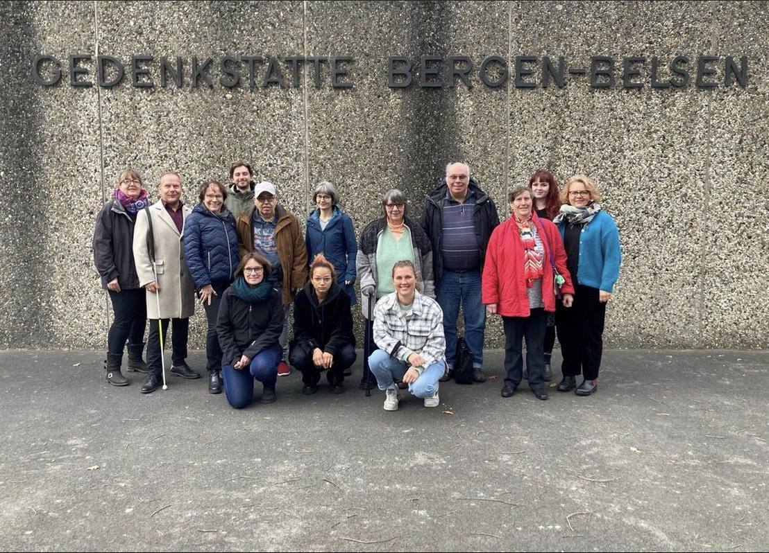 Exkursion der Expertinnen und Experten in eigener Sache in die Gedenkstätte Bergen-Belsen, Gruppenbild vor Waschbetonwand auf dem Anne-Frank-Platz
