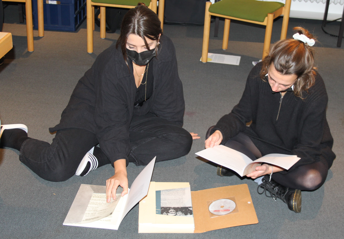 Zwei Teilnehmerinnen sitzen auf dem Boden und sichten historisches Quellenmaterial